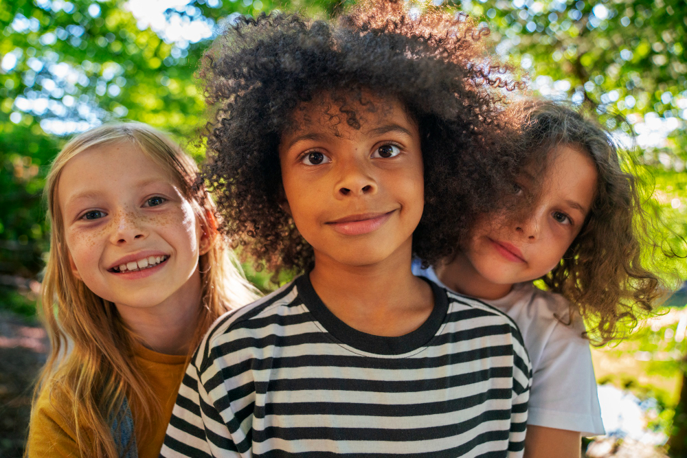 3 enfants souriants en extérieur